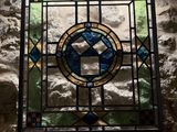 a stained glass window in the corner of a stone wall