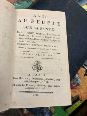 un livre ouvert posé sur une table à côté d'une pile de livres
