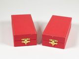 une paire de boîtes à bijoux rouges avec des poignées dorées sur un fond blanc