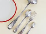 five spoons, a plate, and a fork on a table