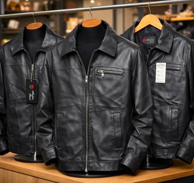 trois vestes en cuir noir suspendues à un portant dans un magasin de vêtements
