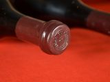 two wine bottles that are sitting on a red cloth