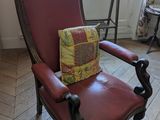 une chaise rouge sur laquelle est posé un coussin, devant une fenêtre