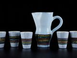 un pichet et six tasses posés les uns à côté des autres sur une table
