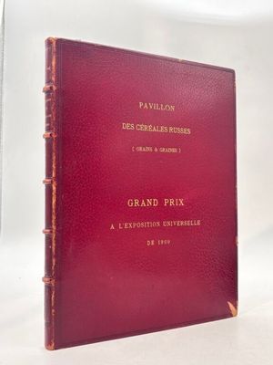 un livre rouge aux lettres dorées posé sur une surface blanche