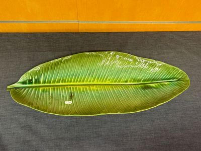 une grande feuille verte posée par terre, près d'un mur jaune