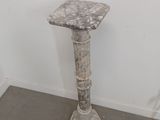 a marble pedestal in the corner of a room
