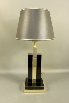 une lampe de table noire et dorée, surmontée d'un abat-jour argenté