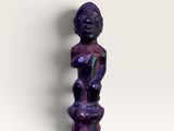 une image représentant une statue violette posée sur une surface blanche