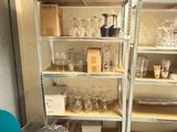 a room with a shelf full of glassware and a table with a blue chair