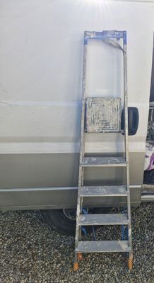 a ladder leaning against a white van with a picture on it