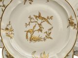 a stack of plates with gold and white designs on them