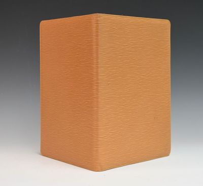 an orange box with a black lid sitting on top of a white surface