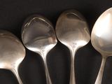 six spoons are lined up in a row on a black surface