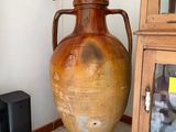 a large brown vase sitting on the floor next to a black speaker