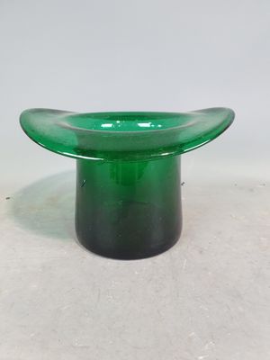 une image représentant un bol en verre vert posé sur une surface blanche