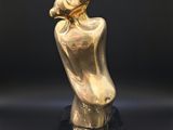a gold sculpture of a woman holding a baby on a black base