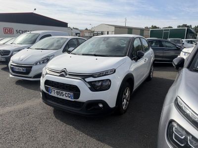 Plusieurs voitures sont garées sur un parking devant un immeuble.
