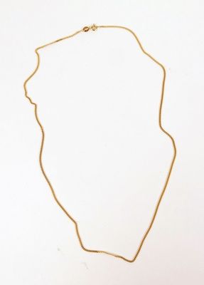 un collier en or avec une longue chaîne posé sur une surface blanche