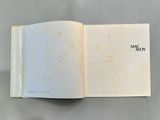 an open book with a white cover and black writing on it
