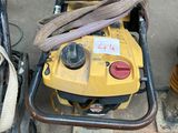 a yellow machine that is on the ground next to a blue bucket