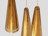 three gold metal lamps hanging from a rope on a gray background