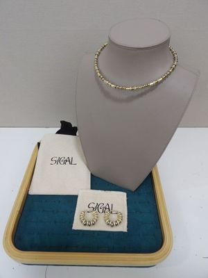 un collier et des boucles d'oreilles présentés sur un plateau, accompagnés d'un petit sac