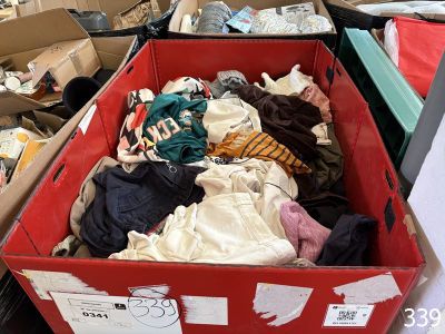 une boîte rouge remplie de nombreux vêtements, posée par terre