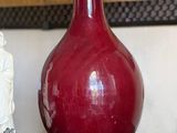 a red vase with a buddha figurine next to it