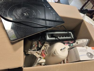 un ordinateur portable et d'autres appareils électroniques dans une boîte posée par terre