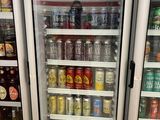 bottles of beer are in a refrigerator at a grocery store