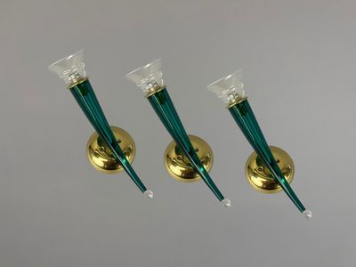 trois bougeoirs en verre vert avec des socles dorés sur fond blanc