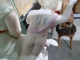 une figurine représentant une femme en robe rose et un homme en costume blanc
