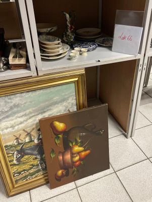 un tableau posé par terre, à côté d'un tableau posé sur une étagère