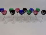 plusieurs verres à vin de couleurs différentes sont alignés sur une surface blanche