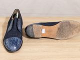 pair of blue shoes on wooden surface with white wall in background