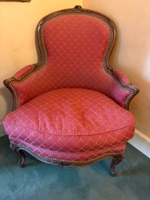 an old chair with a red upholstered seat in a room