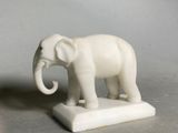 a white elephant statue on a white base on a table