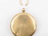 a close up of a gold pocket watch on a white surface