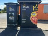 two black trash bins sitting on the side of the road