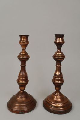 pair of antique brass candlesticks on a grey background