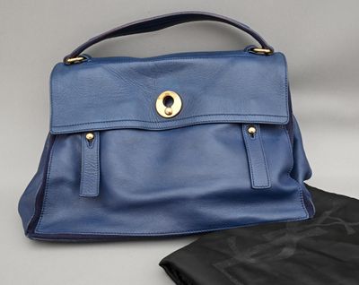 un sac à main en cuir bleu et un pantalon en cuir noir posés sur une table