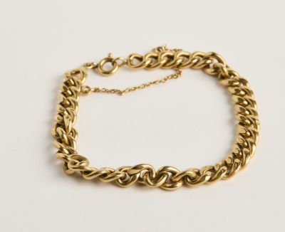 gros plan d'un bracelet en chaîne en or sur une surface blanche