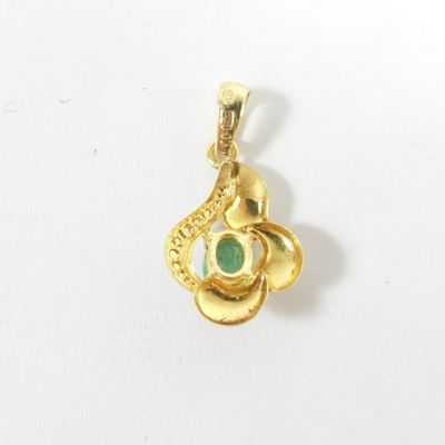 un gros plan d'un pendentif en or orné d'une pierre verte
