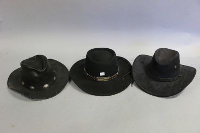 three black hats are lined up on a white surface