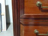 a wooden chest of drawers with brass handles and knobs
