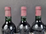 three bottles of red wine are lined up on a table