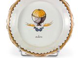 une assiette décorée d'un oiseau, posée sur un socle