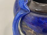 a blue vase with a handle on a white surface