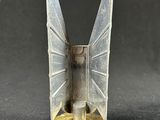 a small metal object with wings on a black surface